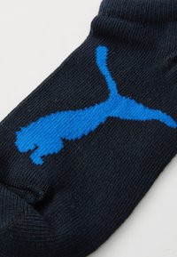 Črne nogavice z modrim, stiliziranim logotipom panterja. Material je tkan, zgoraj pa je rebrasta tekstura za boljši oprijem.