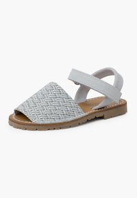 Grijze geweven sandalen met een gestructureerde bovenkant, open te ontwerp en een zachte enkelsluiting. Kenmerken een bruine rubberen zool met gekartelde randen.