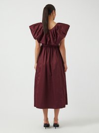 Robe longue bordeaux avec de grandes manches épaules structurées, taille cintrée et jupe fluide ; fabriquée dans un tissu lisse.