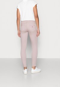 Smal passform, ljusrosa jeans med en slät yta. Har en liten logotyp på bakfickan och femficksdesign. Bärs med vita sneakers.