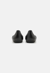 Saboți din piele neagră cu vârf rotund și toc mic. Textura netedă are un design minimal și nu prezintă embellishments vizibile.