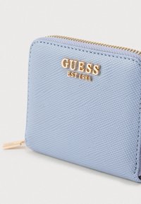 Portafoglio azzurro chiaro, con una texture, dotato di una cerniera dorata e di un logo. Forma quadrata compatta con cuciture visibili e dettagli di motivo delicati.