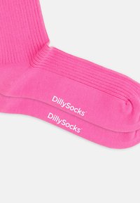 Rosa ribbade strumpor med en slät textur och vit "DillySocks"-logotyp på kanten. De har en enkel, enfärgad design.