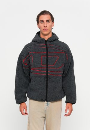 Veste en polaire grise avec capuche, dotée de motifs à rayures rouges. Fermeture à glissière à l'avant, manches larges et matière douce et texturée.