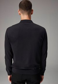 Mustast pikast varrukast pullover särk kitsase lõikega, ribaga mansetid ja äär. Sile tekstuur, minimalistlik disain ja nähtavaid mustreid ei ole.