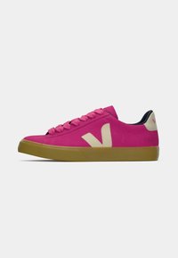 Pink suede sneaker with beige accents, round rubber toe, matching laces, and a textured gum sole; logo displayed on the side and heel.