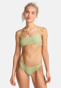 Lichtgroen bikini met ribbeltextuur, voorzien van dunne bandjes aan de bovenkant en een low-rise onderkant. Minimalistisch ontwerp met een uniforme kleur.