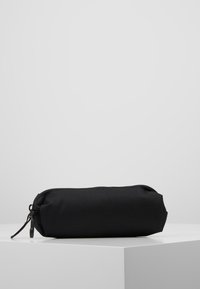 Pochette cylindrique noire en tissu tissé, dotée d'une fermeture éclair et d'une surface texturée robuste ; conçue pour la portabilité et le stockage.