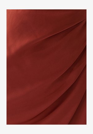 Červená, hladká tkanina s jemnými záhyby a sklady, které ukazují měkkou strukturu a bohatou barevnou hloubku. Žádné viditelné vzory ani akcenty.