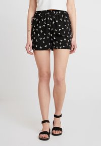 Shorts noirs avec un motif de petits oiseaux crème. Dotés d'une taille élastique pour le confort et une coupe décontractée.