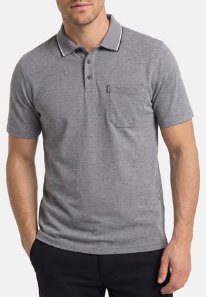 Man draagt een grijs poloshirt met korte mouwen, een kraag, drie knopen en een borstzak, gecombineerd met een donkere broek.