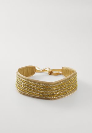 Korálková čelenka se žlutými a stříbrnými korálky na textilním podkladu s hladkým povrchem, zakončená stužkou.