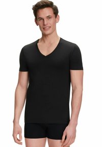 Schwarzes kurzärmliges V-Ausschnitt-T-Shirt aus weichem, glattem Material. Figurbetontes Design mit einem einfachen, sauberen Look, kombiniert mit schwarzen Shorts.