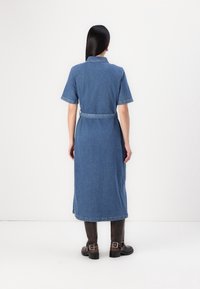 Sukienka koszulowa z denimu z krótkimi rękawami, paskiem w talii i długością do kostek. Posiada klasyczny kołnierzyk oraz jasnoniebieską barwę z równomierną teksturą.