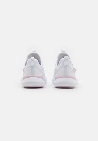 Un par de zapatillas deportivas blancas con acentos en rosa, mostradas desde la parte posterior sobre un fondo blanco, destacando el diseño del talón y las lengüetas.