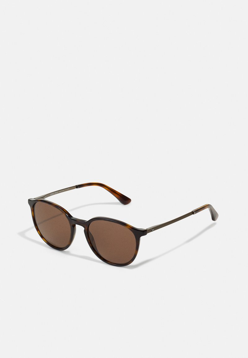 Tortoiseshell sunglasses with brown tinted lenses, round shape, thin metal arms, and unique textured accents on the hinges.