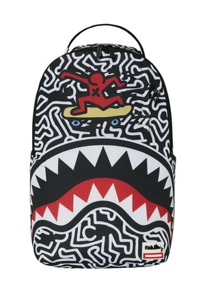 Zaino con un design astratto in bianco e nero, una grafica rossa e gialla di una figura che fa surf e un motivo di denti di squalo bianchi nella parte inferiore.