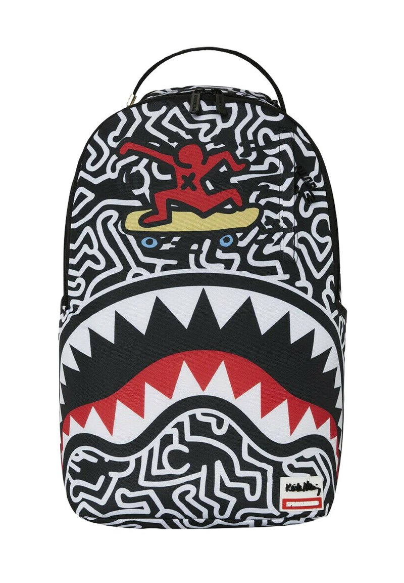 Mochila con un diseño abstracto en blanco y negro, un gráfico rojo y amarillo de una figura surfeando, y un patrón de dientes de tiburón blancos en la parte inferior.