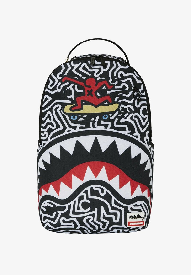 Zaino con un design astratto in bianco e nero, una grafica rossa e gialla di una figura che fa surf e un motivo di denti di squalo bianchi nella parte inferiore.