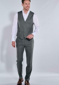 Graue kariertes Weste über einem weißen Hemd, kombiniert mit passenden grauen Hosen und braunen Lederschuhen. Formelles Design, taillierte Silhouette.