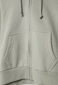 Sweat à capuche gris clair zippé avec poches avant, cordons de serrage et détail bord-côte à l'ourlet.