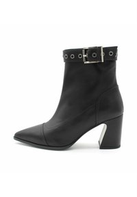 Czarny botek sięgający kostki, z wąskim noskiem, gładką skórzaną teksturą oraz masywnym obcasem. Posiada dekoracyjną klamrę i ozdobne nity na cholewce.