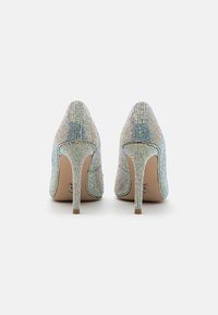 Scarpe con tacco alto con una parte superiore coperta di strass multicolori scintillanti, punta appuntita e un tacco stiletto sottile. Sole color crema.