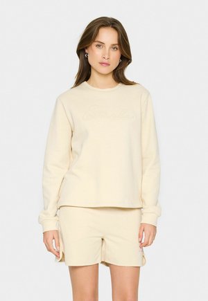 Completo di felpa e pantaloncini color crema realizzato in tessuto morbido; presenta un delicato ricamo "Smile" sul petto e un design dal taglio comodo.