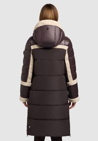 Cappotto imbottito marrone con cappuccio e dettagli in pelliccia sintetica. Presenta una silhouette lunga e un motivo di trapuntatura orizzontale, con polsini foderati in pelliccia.