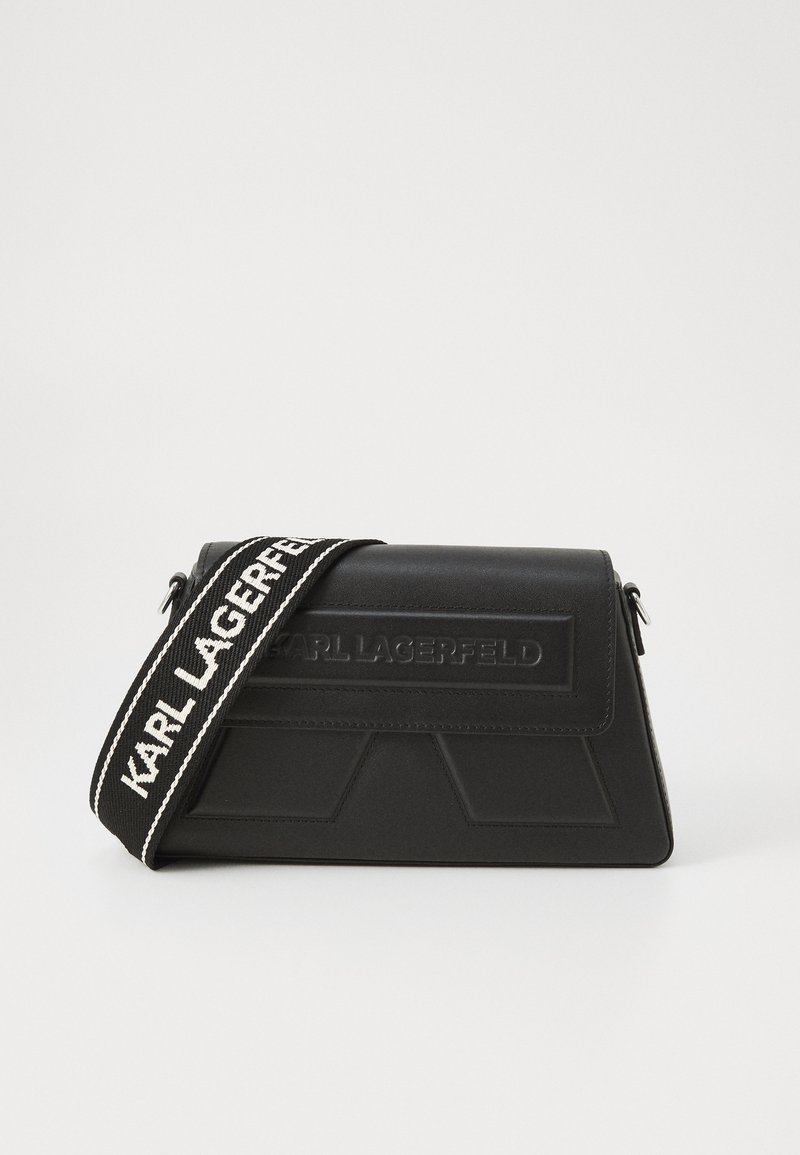 Borsa a spalla nera realizzata in materiale testurizzato con un design triangolare, caratterizzata da una tracolla con logo prominente in bianco e nero.