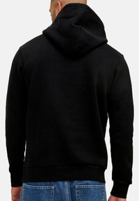 Schwarzer Hoodie mit einer geräumigen Kapuze, langen Ärmeln und einem gerippten Saum. Hergestellt aus weichem Stoff mit einer glatten Textur für hohen Tragekomfort.