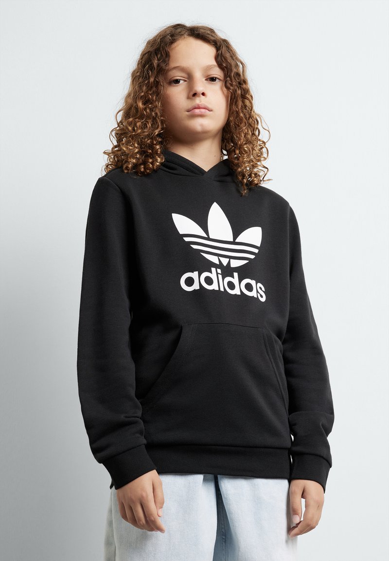 Fekete kapucnis pulóver nagy, fehér Adidas trefoil logóval. Elől zseb található, és húzózsinórral rendelkezik a kapucni. Simább anyagból készült, kényelmes fazonban.