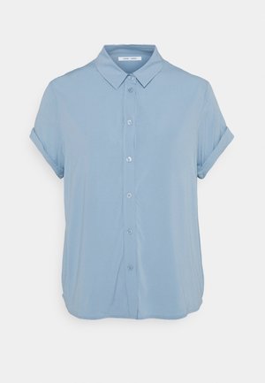 Chemise bleu clair à manches courtes avec boutons, manches retroussées et col pointu, présentée sur un fond blanc uni.
