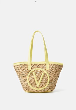 Bolso tote de paja trenzada con ribete y asas amarillas, con un gran logo circular amarillo con la letra V en el frente.