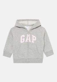 Svetlošedá detská mikina s kapucňou, na zips, s dvoma prednými vreckami a ružovým logom GAP na hrudi.
