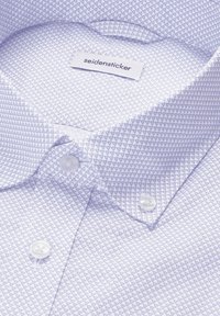 Camicia lilla chiaro con un piccolo motivo a triangoli, caratterizzata da un colletto classico e bottoni bianchi. Etichetta "seidensticker" all'interno del colletto.