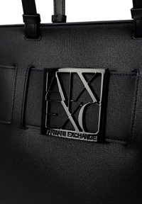 Borsa a tracolla nera in materiale sintetico con finitura testurizzata e un emblema lucido nero con la scritta "Armani Exchange". Spallacci regolabili.