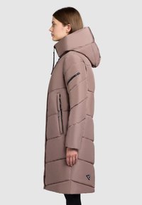 Long, puffy coat in light brown with a hood. Features diagonal quilted design, zippered pockets, and a small logo on the lower side.