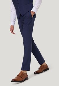 Marineblaue maßgeschneiderte Hosen mit schlanker Passform, Taschendetails, kombiniert mit braunen Leder-Doppelschnallen-Schuhen. Glatte Textur, modernes Design.
