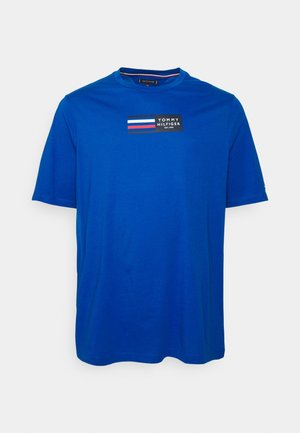 T-shirt bleu à manches courtes avec un petit logo Tommy Hilfiger et des rayures rouges, blanches et bleues sur le haut de la poitrine.