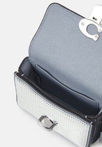 Biała pleciona skórzana portmonetka z srebrnymi akcentami i gładkim szarym wnętrzem. Posiada zapięcie na klamrę oraz wewnętrzną kieszeń na karty.