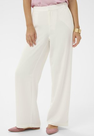 Pantaloni albi cu croială largă, textură netedă și talie înaltă. Prezintă un design simplu și detalii subtile la cusătura frontală, asortați cu balerini roz.