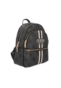 Sac à dos en tissu noir avec deux zips à l'avant, rayures beiges et logo "GUESS". Il présente un matériau texturé et des accents en métal doré.