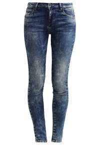 Jean skinny en denim bleu foncé avec un léger effet délavé et des plis sur le devant. Il présente un design classique à cinq poches et une fermeture par bouton métallique.