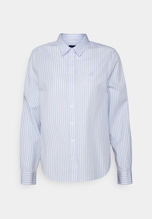 Chemise à manches longues à rayures verticales bleu clair et blanches avec col et logo unique sur la poitrine, sur un fond uni.