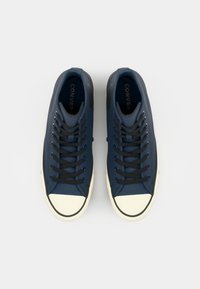 Marineblauwe canvas hoge sneakers met zwarte veters, rubberen neuskap en witte zool, met een gestructureerde bovenkant en logo-detail.
