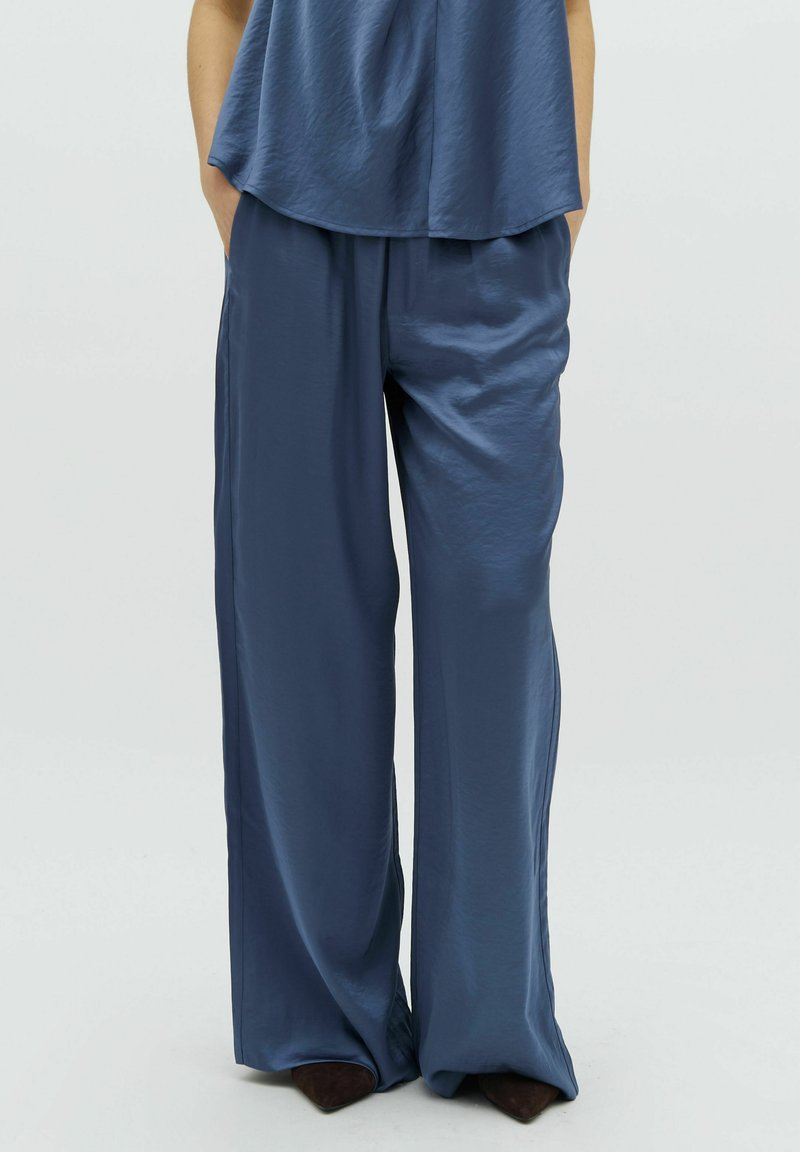 Blue satin wide-leg pants with a smooth texture, featuring an elastic waistband and side pockets, paired with a loose, matching top.
