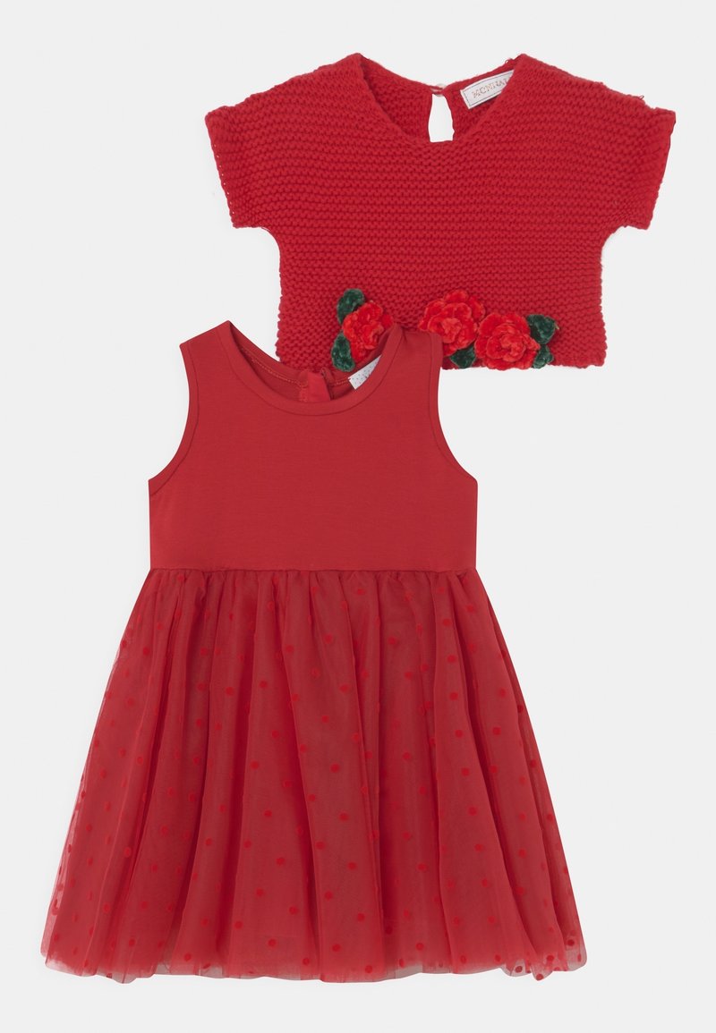 Robe rouge avec un corsage ajusté et une jupe en tulle à pois. Accompagnée d'un boléro en tricot rouge texturé avec des accents floraux.