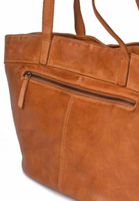 Bruine lederen tas met een gladde textuur, voorzien van een ritszak aan de voorkant en dubbele schouderbanden. Minimalistisch ontwerp met stiksel details.