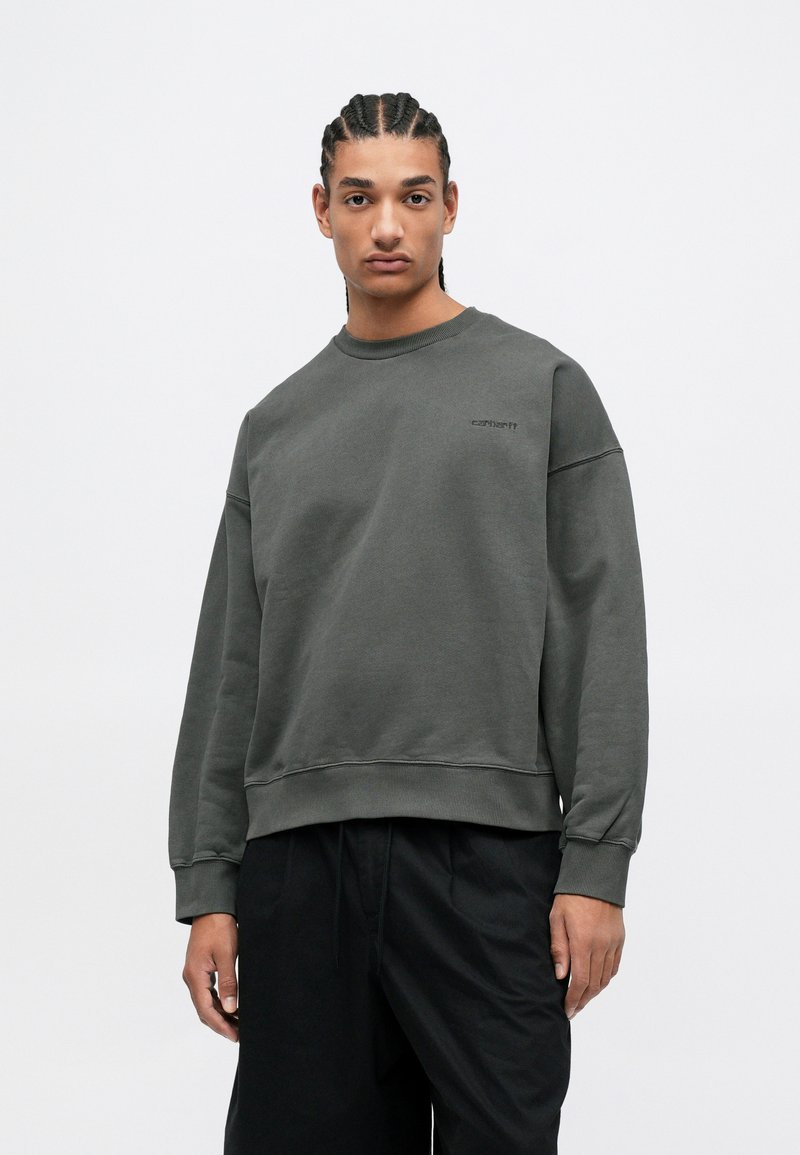 Sudadera gris con mangas largas, puños acanalados y cuello redondo; presenta un pequeño logo en el pecho; está hecha de una suave tela texturizada.